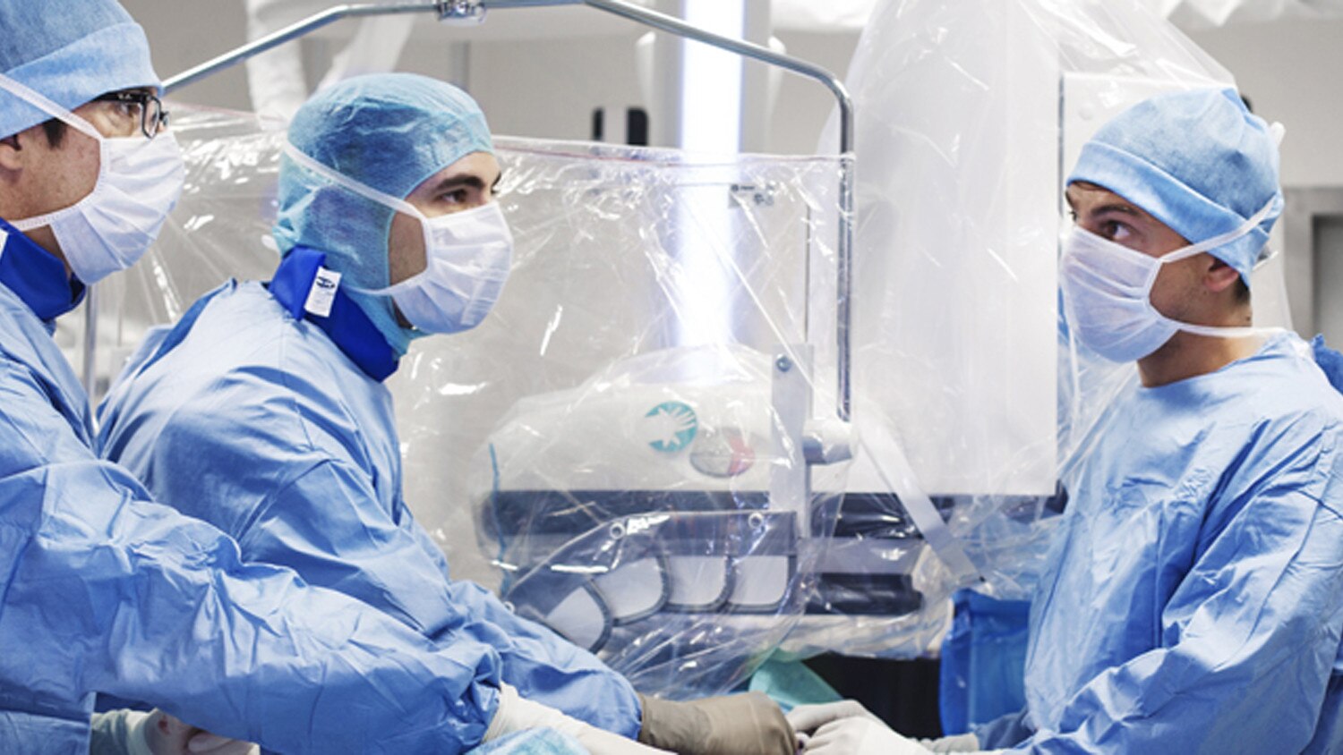 Trois médecins en tenue d'hôpital bleue utilisant les systèmes interventionnels guidés par image.