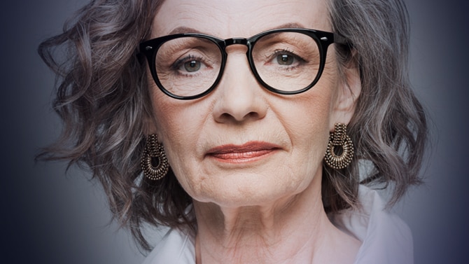 A mature woman wearing glasses faced directly at camera